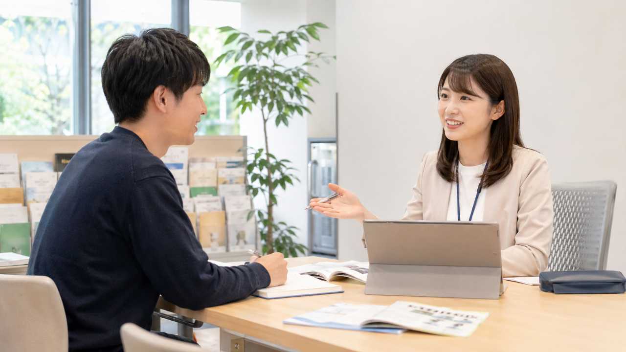 大学のキャリアセンターで学生が相談員と向かい合い、インターン探しについて相談している自然な写真風画像