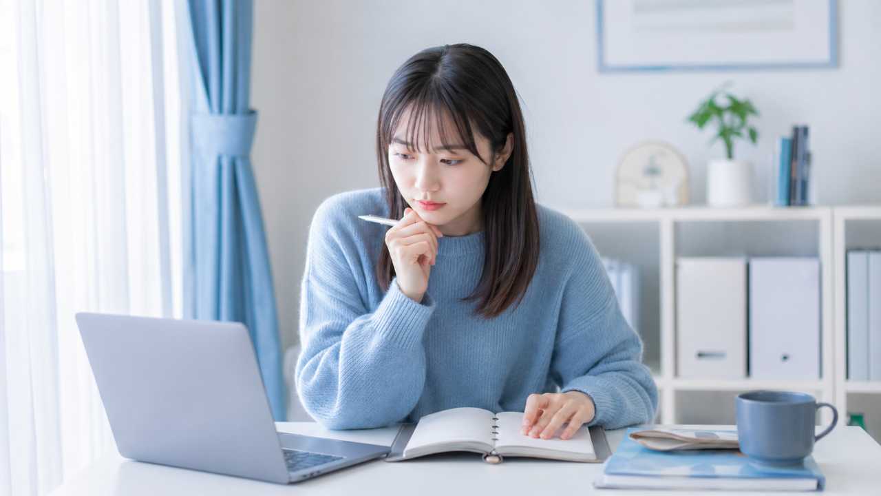 冬の就活シーズンをイメージした写真風アイキャッチ。女子大学生がノートパソコンと手帳を開き、冬インターンの参加社数や企業比較を考えている自然な構図