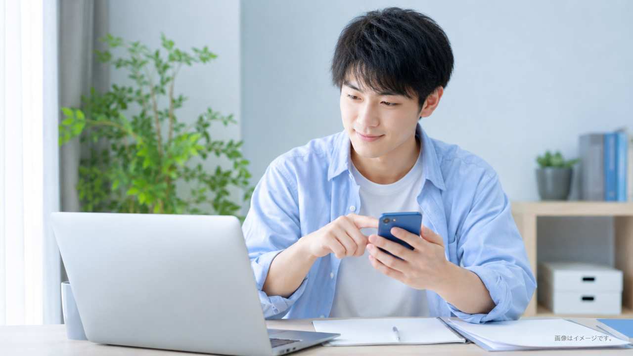 就活中の大学生がスマートフォンとノートパソコンを前に、不要なメール通知を整理して安心した表情をしている実写風写真