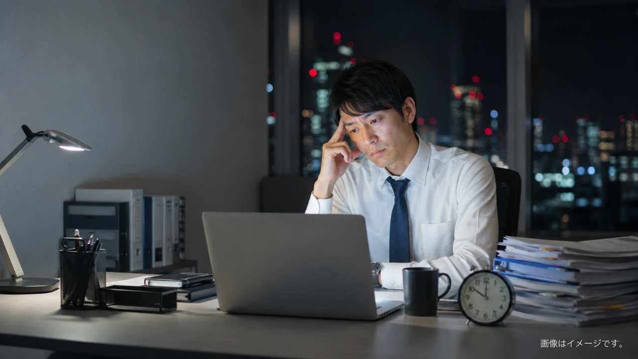 夜遅いオフィスで一人パソコンに向かって働く30代の日本人会社員